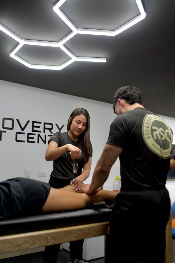 Two physiotherapists providing treatment at a modern clinic with specialized equipment.